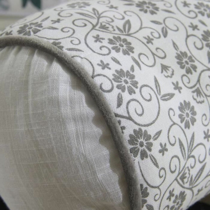 Dekoratives Kissen mit grauem Blumenmuster und Zierleiste.