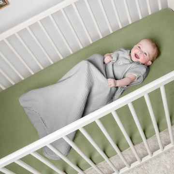 Grauer Ingenuity Schlafsack für 6-18 Monate im Kinderbett. Baby wirkt glücklich und komfortabel.