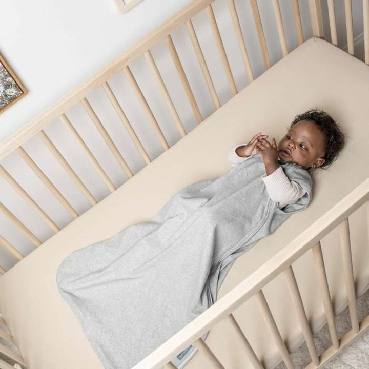 Baby in grauem Baumwoll-Schlafsack (6-18 Monate) in einem Kinderbett für einen sicheren Schlaf.