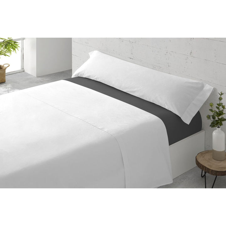 Dunkelgraues Spannbetttuch Paduana auf einem Bett mit weißer Bettwäsche und Kissen.