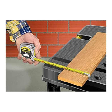 Stanley POWERLOCK Flexometer misst Holz auf Werkbank. Das 5-Meter-Band ist gut sichtbar.