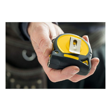 Nahaufnahme: Gelb-schwarzes Stanley Flexometer mit Metallclip in Hand.