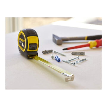 Gelbes Stanley Flexometer mit 8 m Bandlänge, Schrauben und Schraubendreher im Bild.
