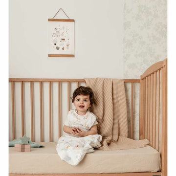 Baby im Tineo Schlafsack mit Wolken Muster im Kinderbett. Süßer Schlafsack für Babys.