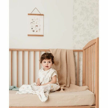 Baby mit Tineo Schlafsack im Kinderbett. Weiß mit Muster für Babys.