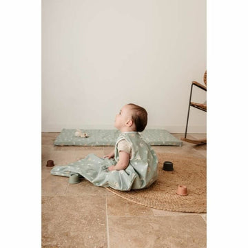 Baby im hellgrünen Tineo Schlafsack mit Muster und passender Spielmatte.