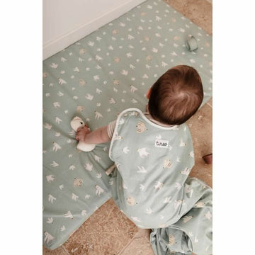 Baby mit Tineo Schlafsack und Spielmatte. Hellblauer Schlafsack mit Vogel- und Bärenmuster.