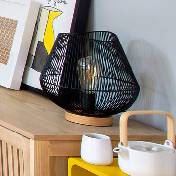 Schwarze Atmosphera Jena Tischlampe aus Metall mit filigranem Drahtdesign und Holzfuß.