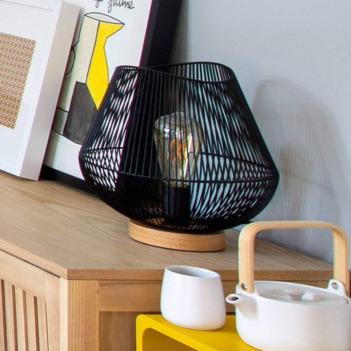 Schwarze Atmosphera Jena Tischlampe aus Metall mit filigranem Drahtdesign und Holzfuß.
