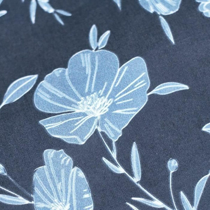 Nahaufnahme: Floraler Bettdeckenbezug in Dunkel mit hellblauen Blumen.