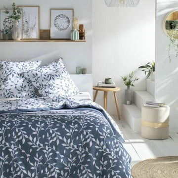 Blauer Bettdeckenbezug mit Blumenmuster in einem hellen Schlafzimmer. Elegante Bettwäsche.