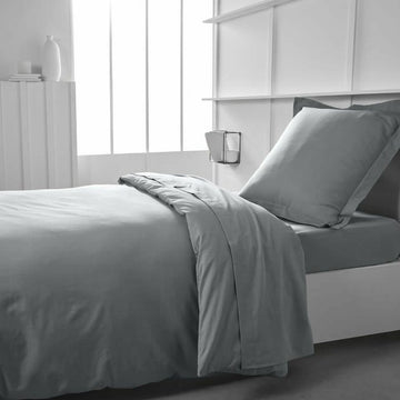 Helles graues Jersey Spannbetttuch 90x190 cm auf einem Bett. Weiche Textur.