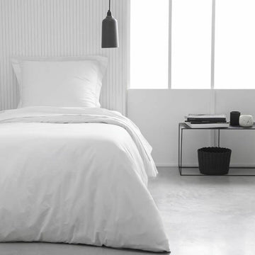 Weißes Spannbetttuch Essential 90x190 cm auf einem Bett. Glatte, klare Passform.
