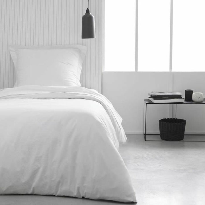 Weißes Spannbetttuch Essential 90x190 cm auf einem Bett. Glatte, klare Passform.