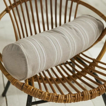 Beige Kissen mit Streifenmuster auf einem Rattanstuhl. Dekokissen Detail.