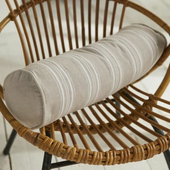 Beige Kissen mit Streifenmuster auf einem Rattanstuhl. Dekokissen Detail.