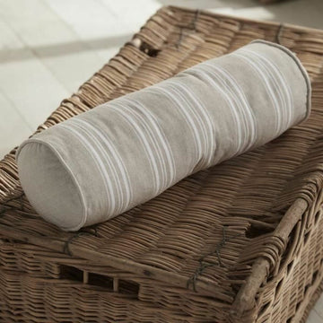 Beige Kissen mit Streifenmuster auf einem Weidenkorb. Dekokissen.