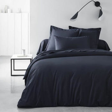 Dunkelblaues Spannbetttuch 140x200 cm auf einem Bett. Marineblau und glatt.