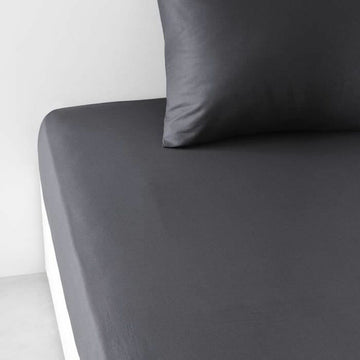 Anthrazit Spannbetttuch Essential auf einem Bett mit passendem Kissenbezug.