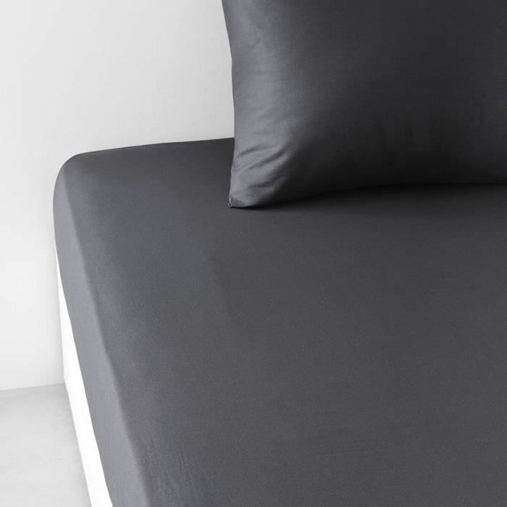 Anthrazit Spannbetttuch Essential auf einem Bett mit passendem Kissenbezug.