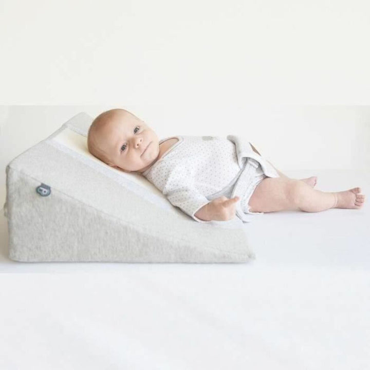 Baby ruht auf Domiva 3D WAVE Kissen. Das Kissen ist hellgrau und dreieckig für eine geneigte Fläche.