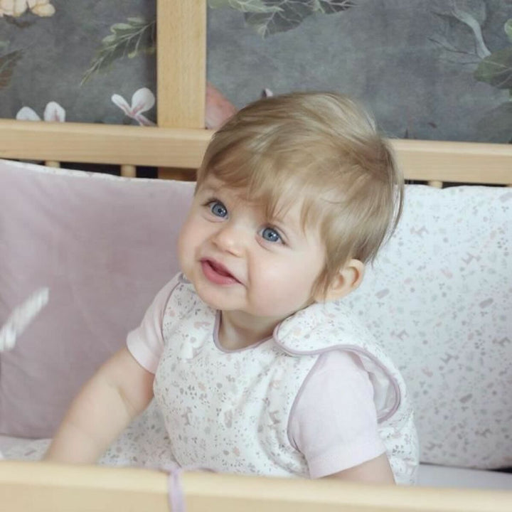 Baby im beigen Domiva Schlafsack (0-6 Monate) mit Muster im Kinderbett.