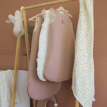 Verschiedene Domiva Babyschlafsäcke 0-6 Monate auf einer Holzstange, darunter ein Schlafsack mit Halbmond.