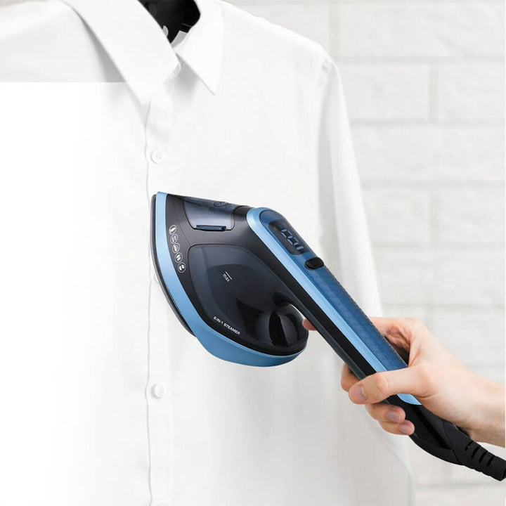 Blau-schwarzer Feel Maestro MR-315C Dampfreiniger bügelt ein weißes Hemd. Wassertank und Digitalanzeige.