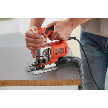 Orange Black & Decker Laubsäge schneidet Holz. Staubabsaugung ist auch sichtbar.