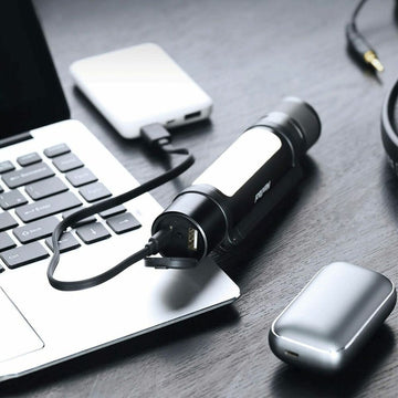 Schwarze Taschenlampe 1000lm mit USB-Anschluss wird geladen. Lichtpanel und Aluminium-Design.
