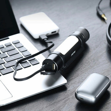 Schwarze Taschenlampe mit USB-Anschluss wird aufgeladen. Modernes Design mit hellem Lichtpaneel.