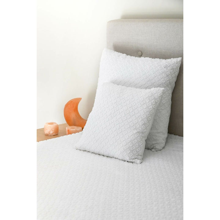 Weißes ESPRIT Home Kissen mit Textur auf einem Bett. Quadratisches Kissen.