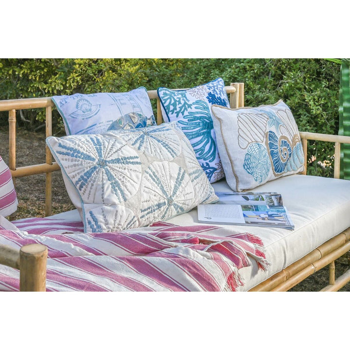 Mediterranes Kissen mit Muschel- und Korallenmuster auf einer Bambusbank. Dekokissen im maritimen Stil.