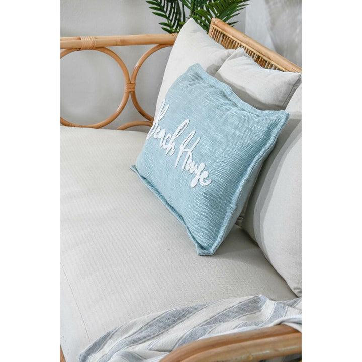 Helles ESPRIT Kissen "Beach House" in Himmelsblau mit weißer Schrift auf Sofa.