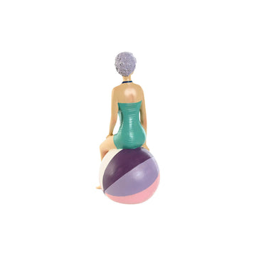 Türkis-lila Deko-Figur im mediterranen Stil. Frau sitzt auf gestreiftem Ball. Sommerliche Dekoration.
