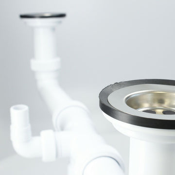 Weißer Spülbecken Siphon mit silbernem Abfluss und schwarzen Gummidichtungen.