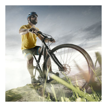 Fahrradfahrer mit Fahrrad in der Natur. Das Kabel mit Vorhängeschloss von Ferrestock schützt vor Diebstahl.