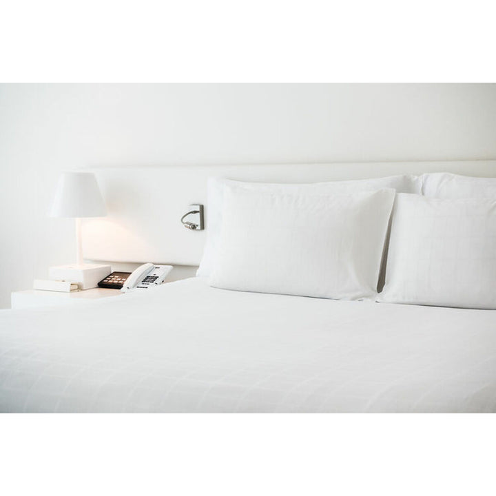 Weißes Hosteline IRIS PREMIUM Oberlaken, Double size, auf einem Bett mit Kissen.
