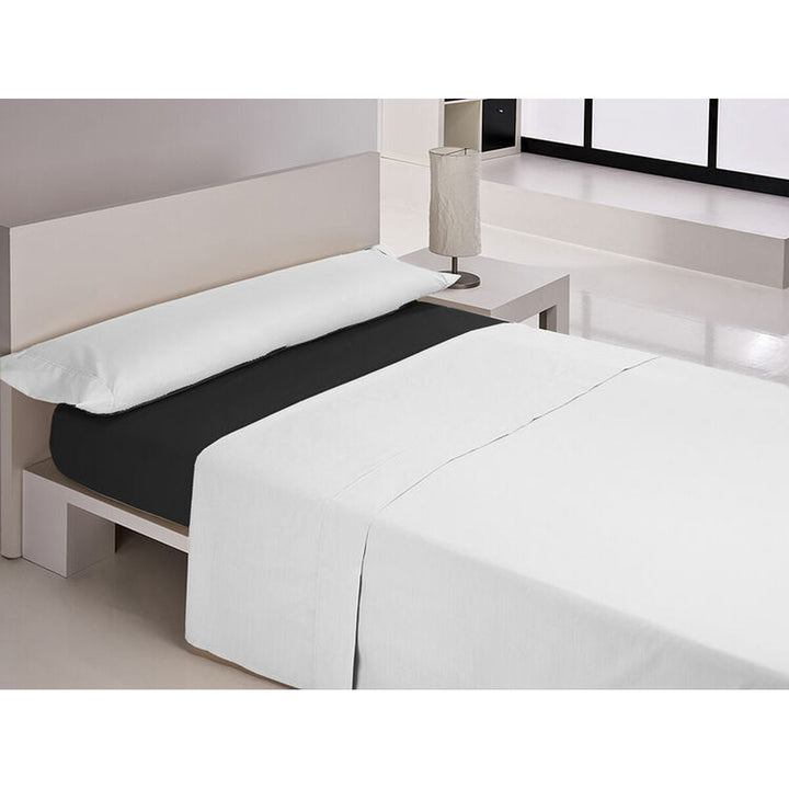 Schwarzes Spannbetttuch auf Doppelmatratze mit weißen Laken und Kissen im Schlafzimmer.