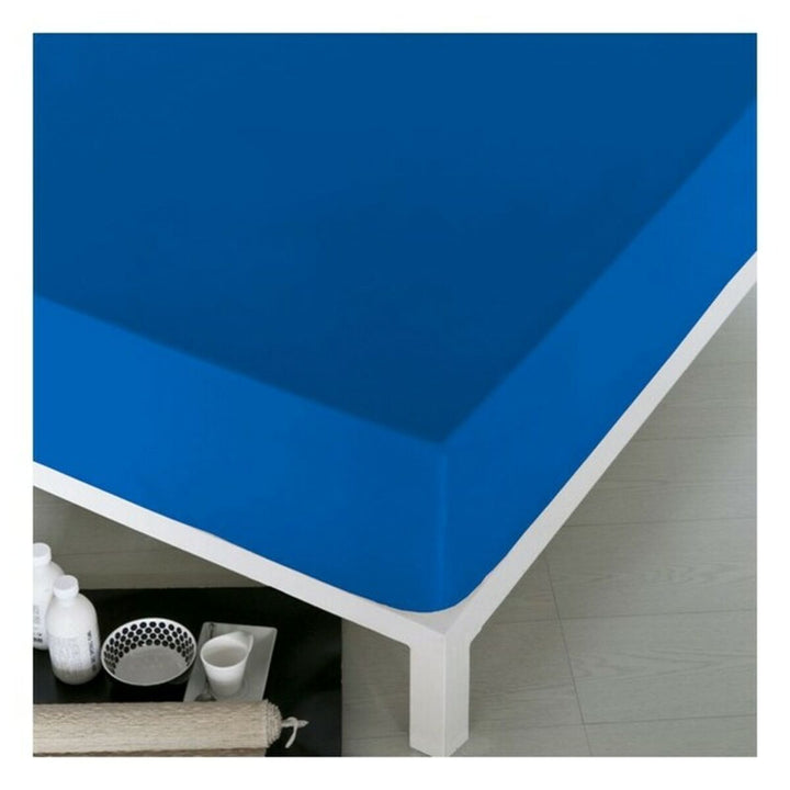Blaues Spannbetttuch Naturals auf einem Bett. Glatte Textur und lebendige Farbe.
