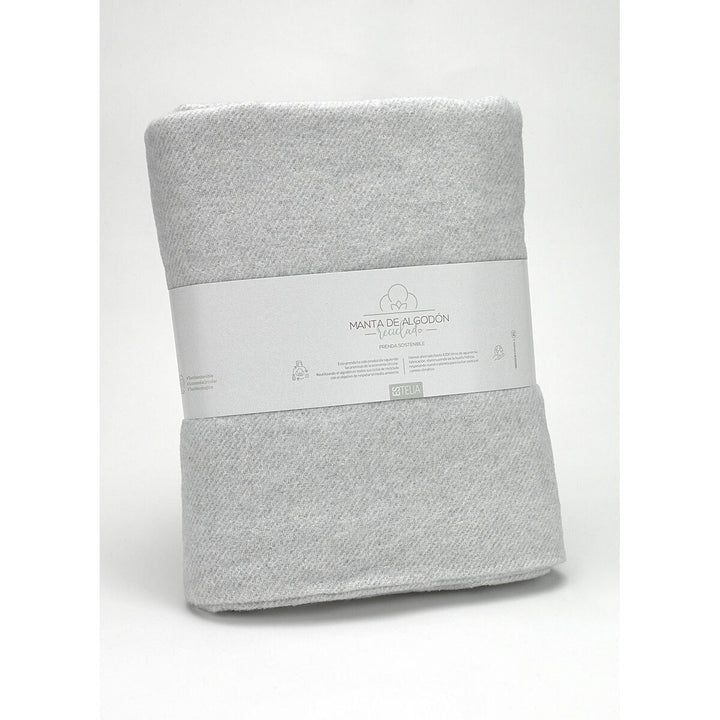 Helle, perlgraue Decke aus recycelter Baumwolle. Weiche Textur und nachhaltige Produktion.