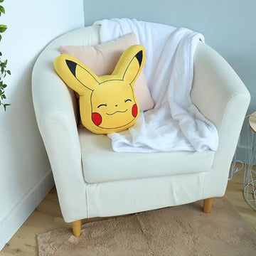 Gelbes 3D Pikachu Kissen mit roten Wangen auf einem Sessel. Niedliches Pokémon Kissen.