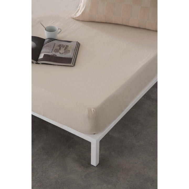 Beige Spannbetttuch Naturals ELBA (135x200) auf einem Bett. Entspannende Atmosphäre.