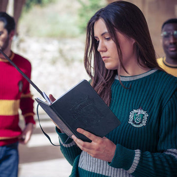 Grüner Harry Potter A5 Notizblock mit Slytherin Wappen, gehalten von Person im Slytherin Pullover.