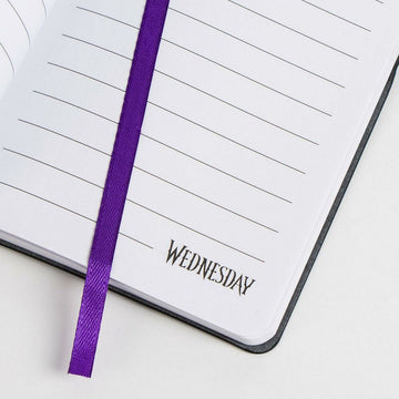 Schwarzer Notizblock Wednesday mit liniertem Papier und lila Lesezeichen.