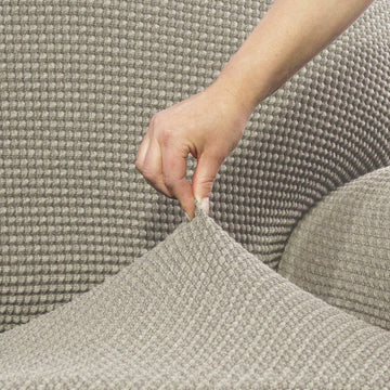 Nahaufnahme: Beige Ohrensesselhusse mit Waffelmuster wird angepasst.