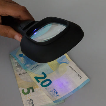 Schwarze Lupe mit LED- und UV-Licht prüft Euro-Banknoten auf Echtheit. Sicherheitsmerkmale sichtbar.