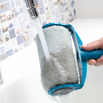 Blauer, nachfüllbarer Roll'n'paint Farbroller wird unter einem Wasserhahn gespült.