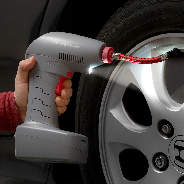 Grauer, tragbarer Luftkompressor mit LED pumpt einen Reifen auf. Airpro+ mit rotem Schlauch.