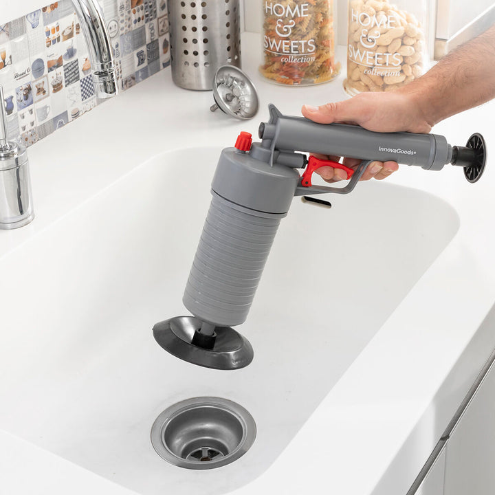 Graue KlinGun InnovaGoods Abflussreinigungspistole mit Adaptern im Waschbecken. Universelle Anwendung.